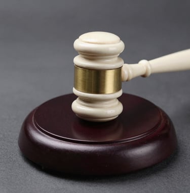 Clean, minimalist photography of an ivory gavel on a polished dark wood base, highlighting textures and metallic gold bands.