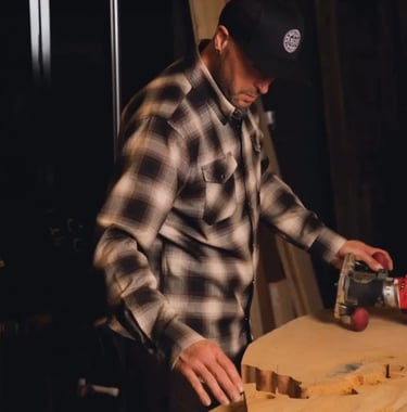 Basile in a plaid shirt and a hat is making a Mended Heart