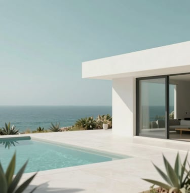 A shot of a minimalist luxury villa overlooking the ocean, clean lines, white walls, and sage green plants, #FAF8F5 and #7E8A7F.