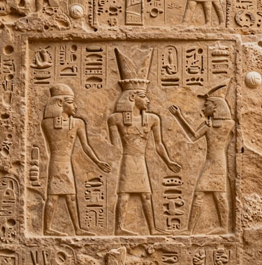 Macro photography of intricate ancient hieroglyphics carved into a desert sand colored stone wall in a North African / Egyptian temple, with soft side-lighting highlighting the relief details.