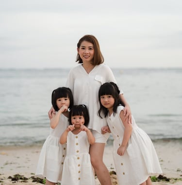 Mother and daughters standing together by the ocean during a family photography session at The Mulia Nusa Dua Bali
