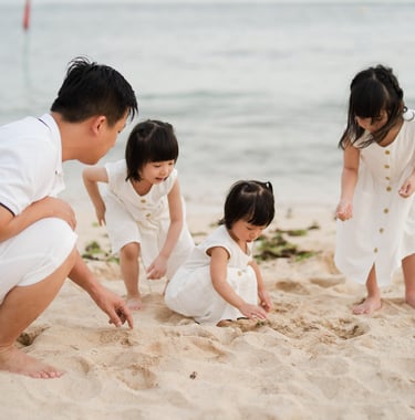 Father and children playing with sand on the beach at The Mulia Nusa Dua Bali during a relaxed family photo session