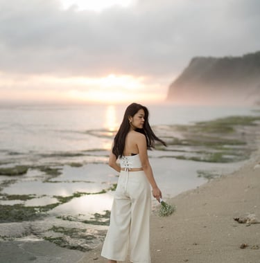Bride walking along coastal shoreline during sunset at Melasti Beach Bali