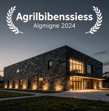 A professional architectural photograph of a modern, minimalist agribusiness processing facility at dusk. The building features crisp lines and dark stone cladding, illuminated by soft golden exterior lights under a dark charcoal sky.