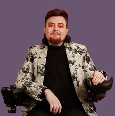 Jamie Hale, a white electric wheelchair user wearing a silver floral jacket