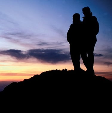 a couple of people standing on a mountain top
