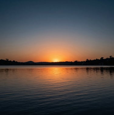 Atmospheric shot of a sunset over the lake in Formosa, Goiás, with dark blue and orange tones, reflecting a premium and calm lifestyle.