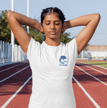 Young woman stretching in a white branded t-shirt on a red running track at an outdoor stadium.
