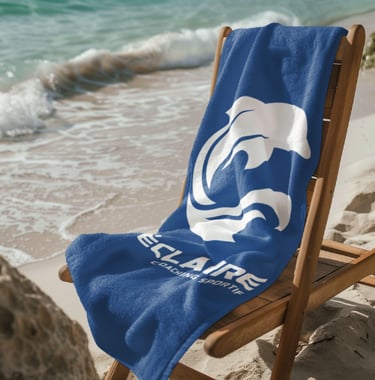 Une serviette de plage personnalisée avec un logo de dauphin blanc sur une chaise près de l'océan.