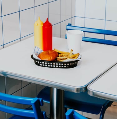 Burger amb patates i salses servides en una taula de Flipa amb estètica minimalista blava i blanca