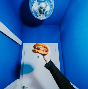 Burger de Flipa sostinguda sota una bola de discoteca en un espai blau, estil original i atrevit