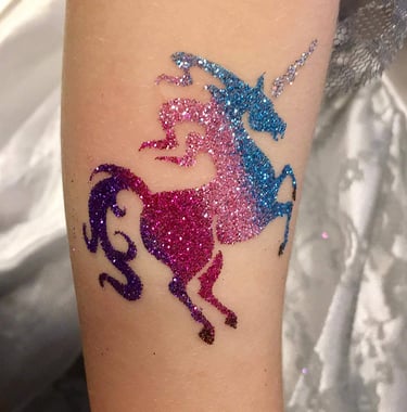 a unicorn glitter tattoo on a woman's arm