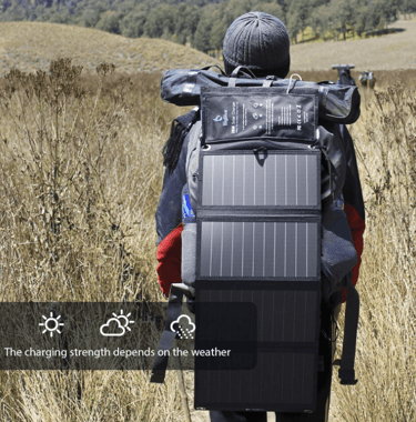 Backpacker using a BigBlue Solar Charger harnessing sunlight to power devices while hiking
