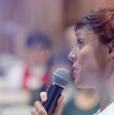 a-female-business-executive-holding-a-microphone-addresses-group