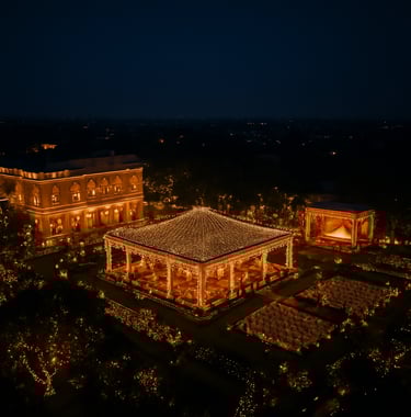 A breathtaking high-angle aerial drone photograph of a grand South Asian outdoor event venue at night in Pune, featuring elegant fairy lights, dark navy skies, and vibrant artistic composition.