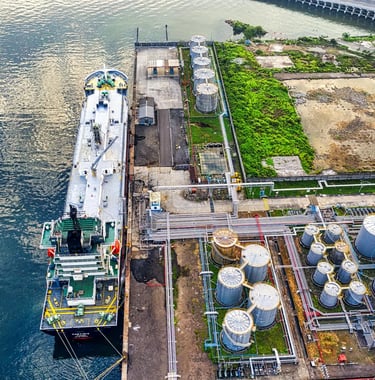 a large ship in the water with a large tanks in the background
