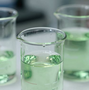 Close-up of high-precision laboratory glassware filled with clear and light green fluids, sharp focus on liquid meniscus, sterile environment, soft bokeh background.