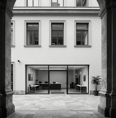 Black and white photograph of a minimalist, modern office lobby in a historic European building, showing a blend of old and new.