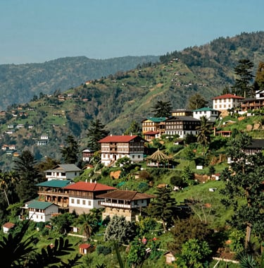 Photography of a scenic mountain vista in Shimla, featuring traditional colonial-style architecture nestled among lush green hills under a bright clear sky, South Asian region, vibrant and inviting.