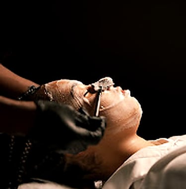 Jeune femme qui se fait appliquer un masque par une esthéticienne