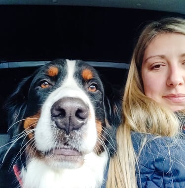 a woman in a blue jacket and a dog in a car