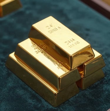 A close-up photograph of several stacked 24-karat gold bars stamped with quality marks, resting on a velvet dark teal surface. Warm lighting reflecting off the polished gold. Middle Eastern / Gulf luxury market style.
