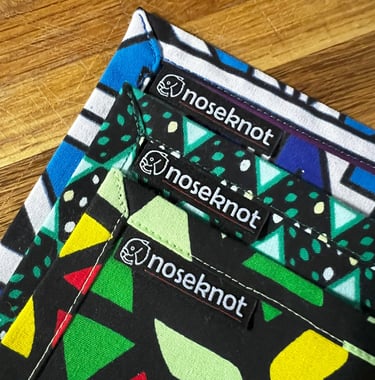 Three vibrant Noseknot handkerchiefs showing the stitching, corners and Noseknot labels