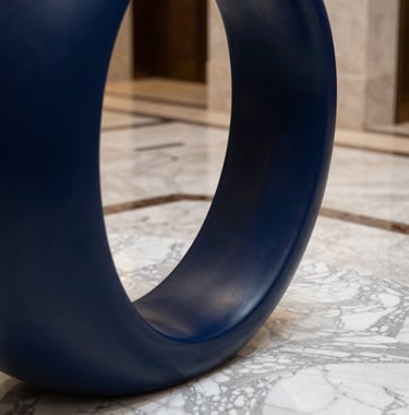 A close-up of a high-end hotel lobby detail, featuring marble floors and a minimalist sculpture in navy blue. The style is modern and premium. Global / Sophisticated Traveler environment.