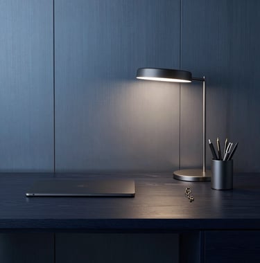 An executive desk setup in dark navy wood with a minimalist lamp and high-end stationery, set against a steel blue wall background.