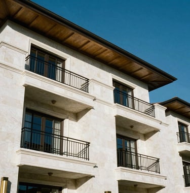 Architectural detail of a luxury villa in a South American / Ecuadorian residential complex. White stone walls, black metal balcony railings, and gold accents. Clear blue sky, sharp focus.