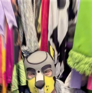 Man in pup mask sitting in his closet.