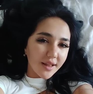 lady lying on bed with white dress taking a selfie