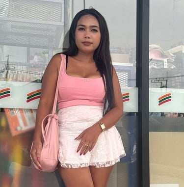 Lady leaning against a shop window wearing short white skirt and sleeveless pink top