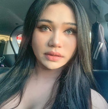 Facial shot of ladyboy looking straight and wearing a low cut gold sequence dress