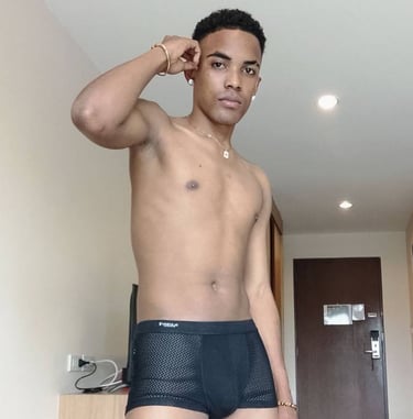 Man standing and wearing black boxer style underwear with his right hand up against his ear