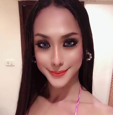 Ladyboy with long black hair wearing a sexy pink and white dress