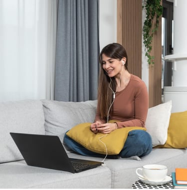 a woman sitting on a couch with a laptop and headphones