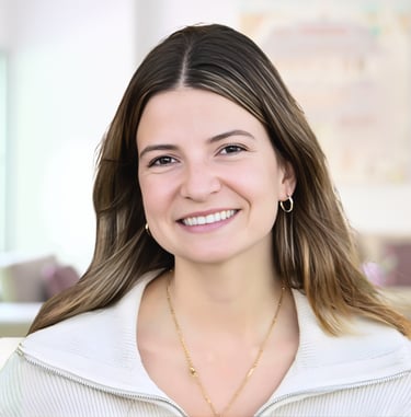 Smiling woman with long brown hair wearing a white zip-up sweater and gold jewelry.