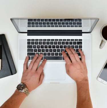 a person's hands typing on a laptop computer