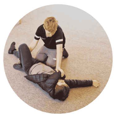 a boy placing another boy into the recovery position during a Frist Aid workshop