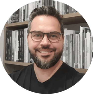 Consultor de valuation e avaliação de empresas de óculos sorrindo em frente à uma estante de livros