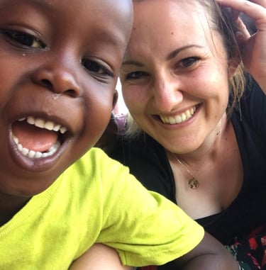 Bild von Nadja mit einem fröhlichen Kind aus Uganda
