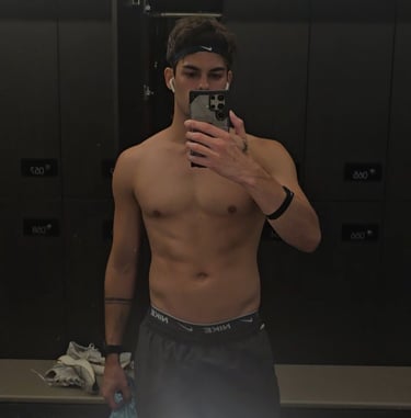 man taking a photo looking into a mirror wearing grey shorts
