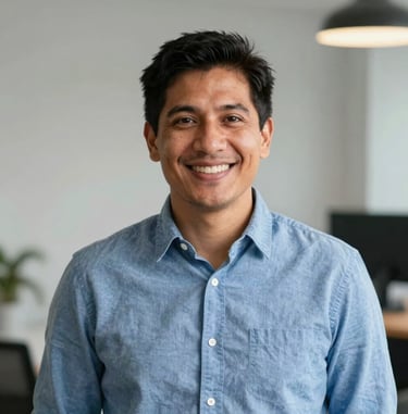 A professional portrait photo of a South American male digital creator with a warm smile, wearing a casual smart blue shirt. Clean, soft indoor office lighting, highly professional and approachable.