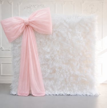 Elegant white tulle backdrop with a large decorative pink bow for events.