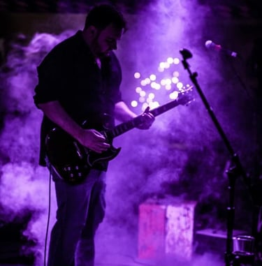 John playing guitar with purple smokey background