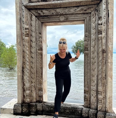 Edyta Vorilhon passant une porte en pierre au bord de l'eau.