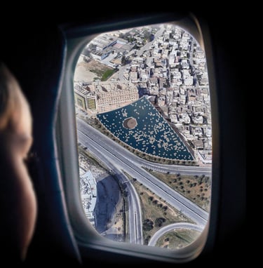 A photo of a child looking through an airplane window at a giant solar roof