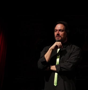 a man in a black shirt and green tie dye on a stage