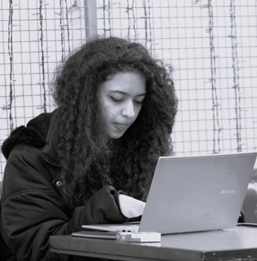 a woman with curly long hair sitting at a table with a laptop